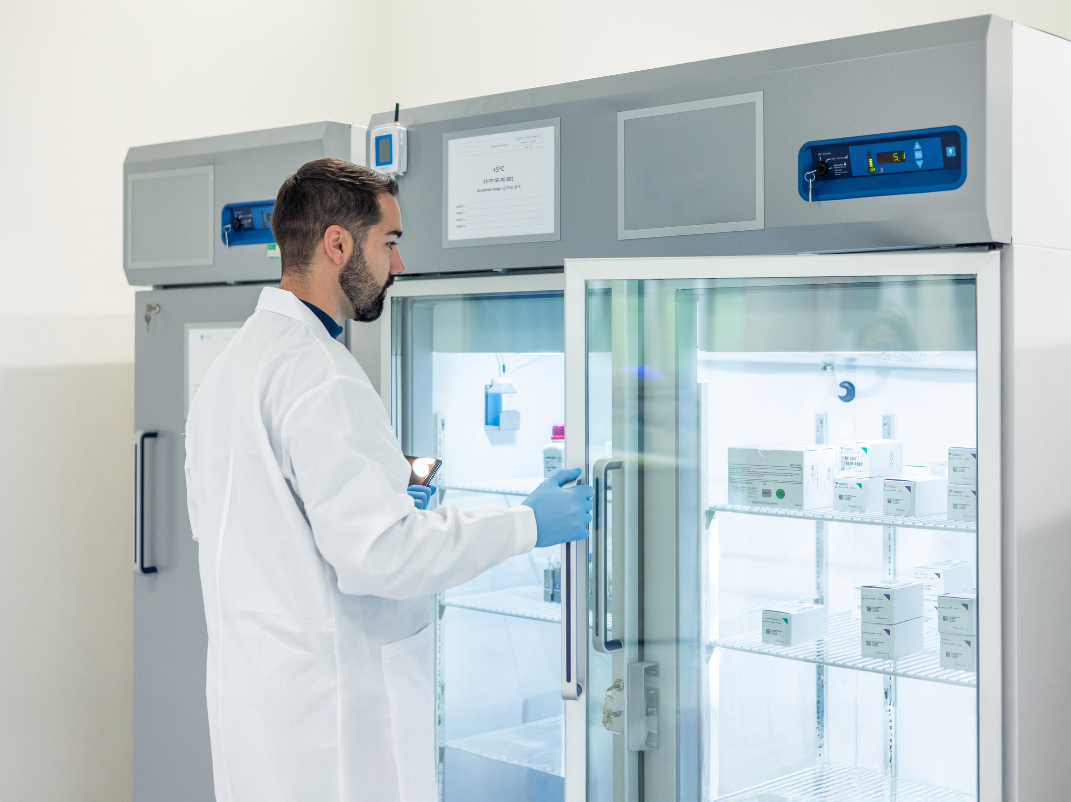 Scientist opening laboratory refrigerator containing medicines and vaccines lab technician extracting samples from test tubes